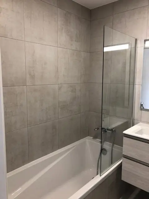 Banheira com resguardo de vidro e revestimento cerâmico cinzento
