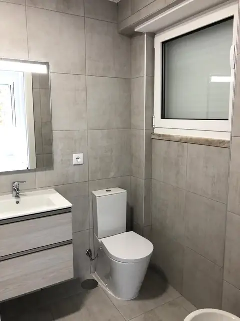 Casa de banho com móvel suspenso, sanita e revestimento cinzento