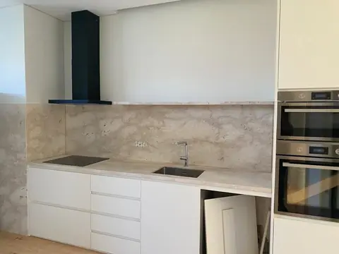 Cozinha branca com frente em efeito pedra, fornos encastrados e exaustor preto